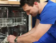 Dishwasher repair technician inspecting and servicing an open dishwasher in Reno, NV