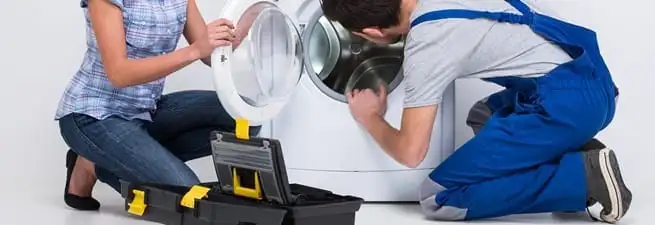 Washer repair technician inspecting a front-load washing machine with tools in Reno, NV