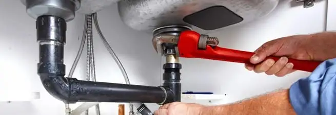 Garbage disposal repair technician tightening the sink drain and disposal connection in Reno, NV