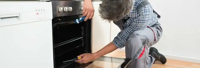 Oven repair technician inspecting and servicing an electric oven in Reno, NV