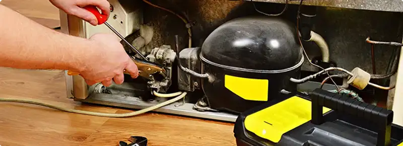 Refrigerator repair technician fixing the compressor and wiring in Reno, NV