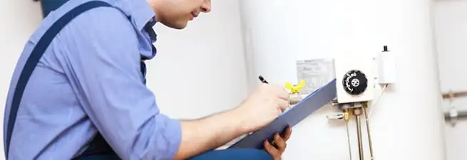 Water heater repair technician inspecting the unit and recording service notes in Reno, NV